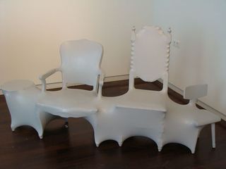 Three chairs and a table all coated in white plastic to make them into one piece