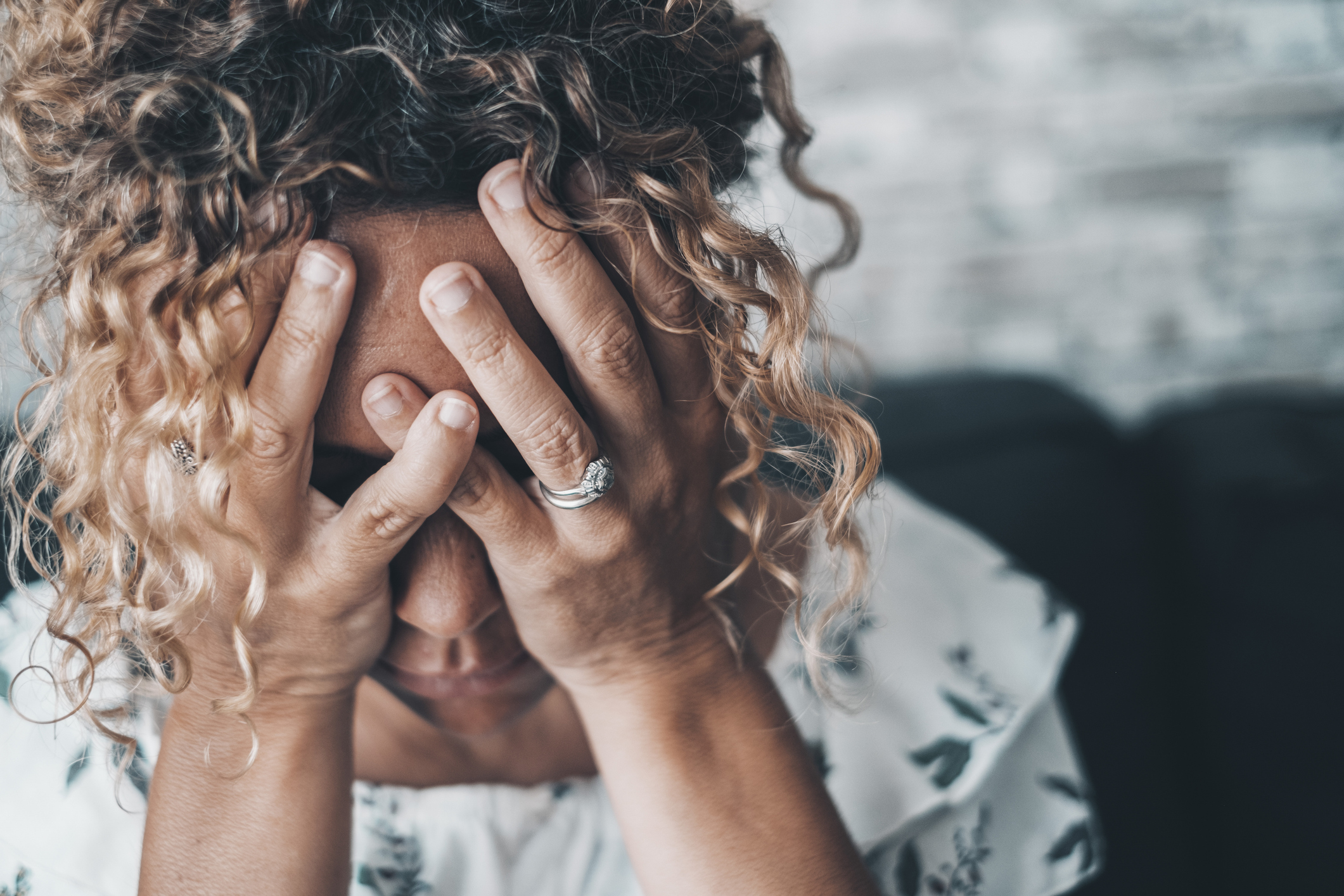 Woman who has lost cryptocurrency holds her head in her hands