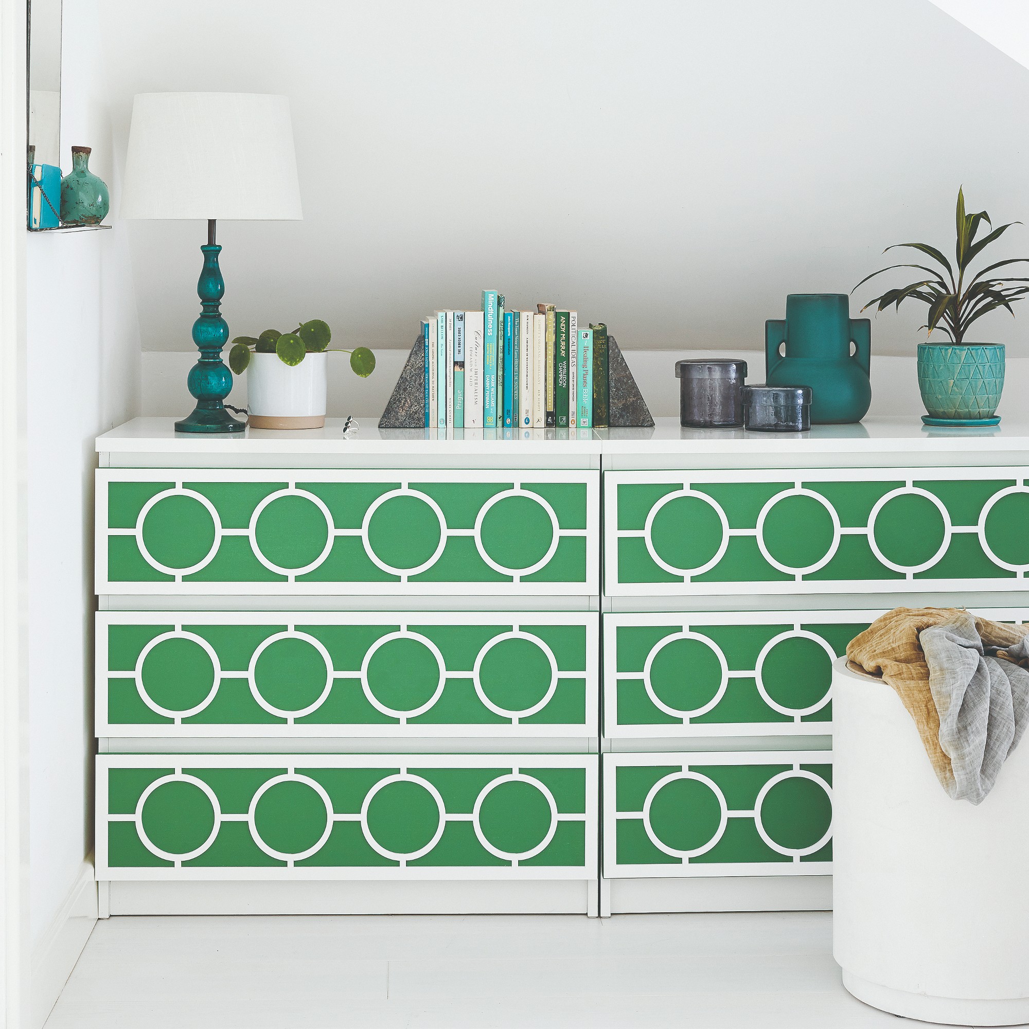 A patterned green chest of drawers in a white-painted room