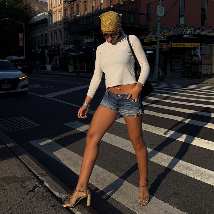 Aisha wears white top with jean shorts, a bandana, and heels. 