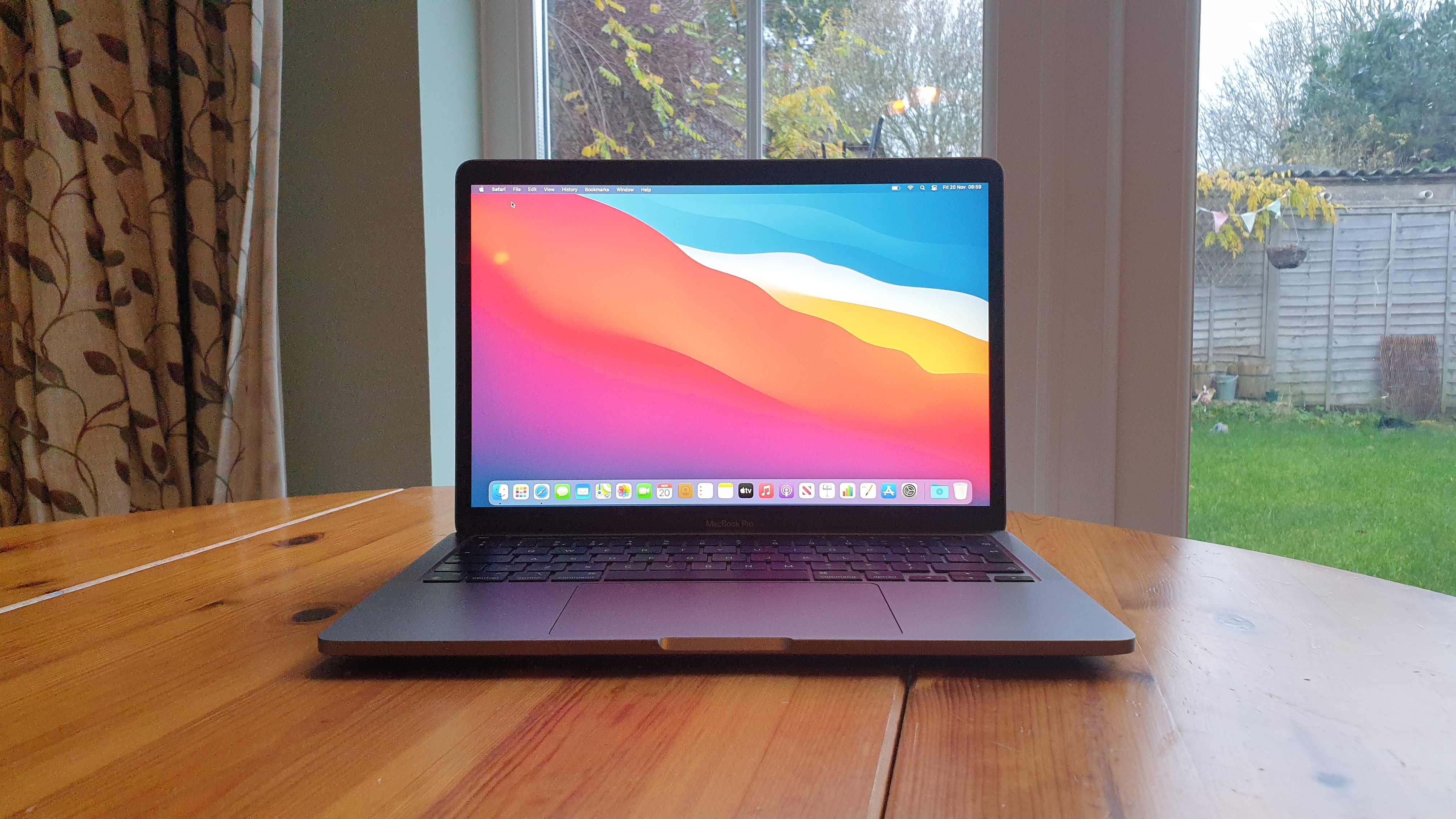 MacBook Pro 13-inch (M1, 2020) on a wooden table with a garden in the background