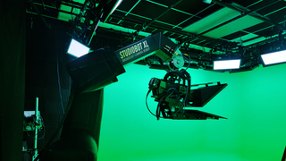 Shows a green screen of a studio with a robotic camera arm