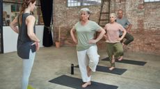 Line of seniors balancing on one foot, with an instructor facing them