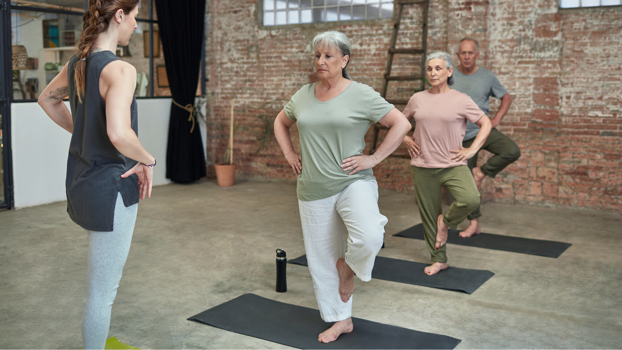 Line of seniors balancing on one foot, with an instructor facing them
