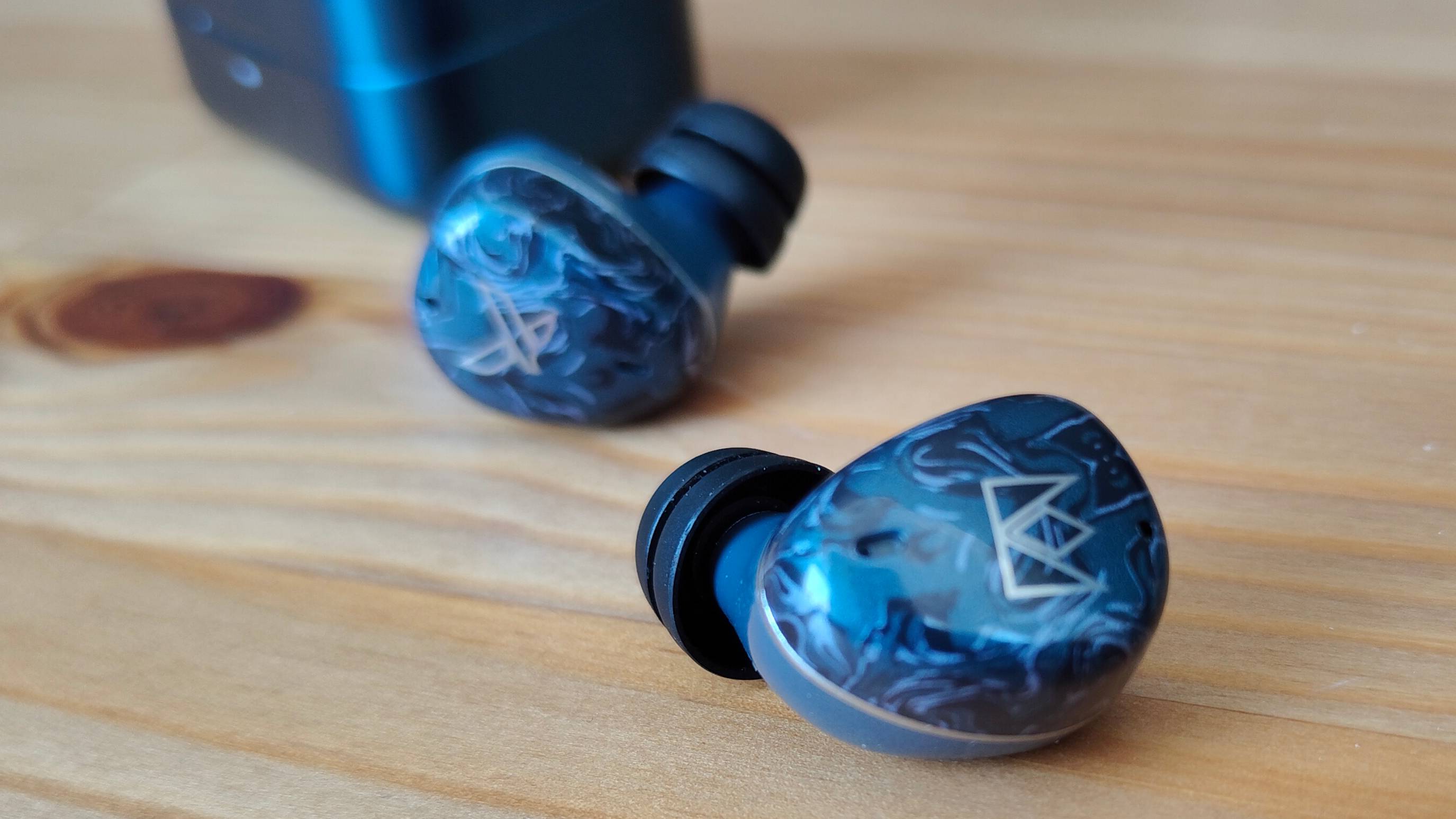 The Noble Osprey earbuds on a wooden table.
