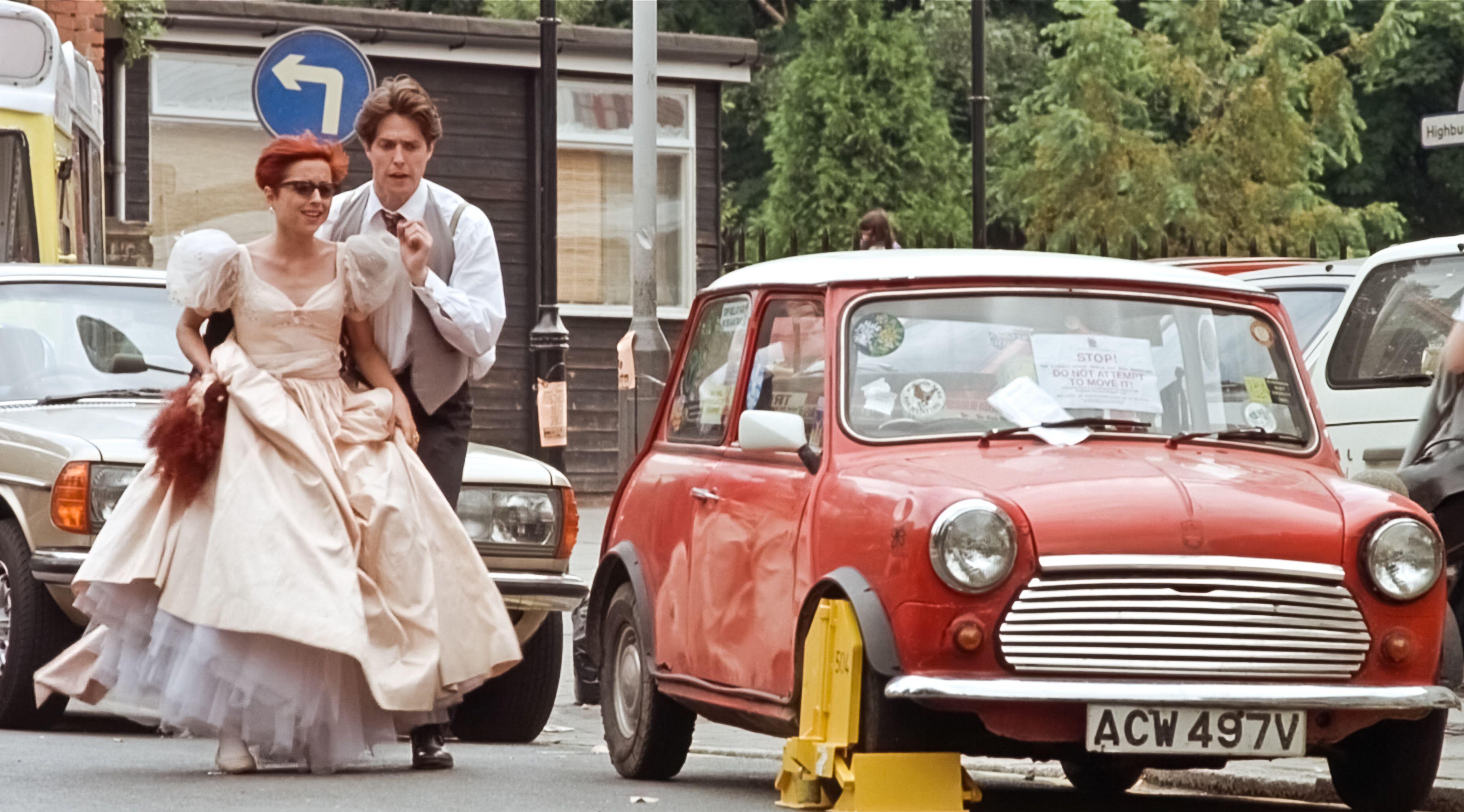 Hugh Grant in Four Weddings and a Funeral running through London next to a red Mini