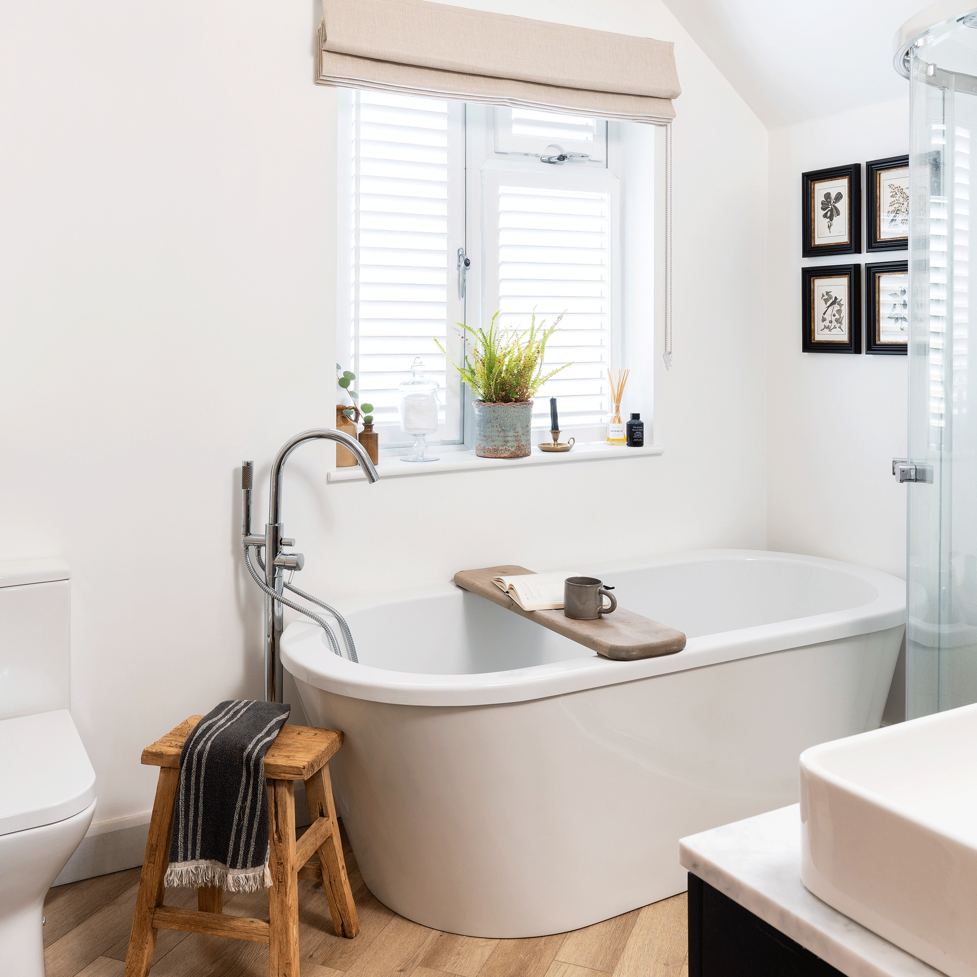 a neutral bathroom with white modern bath tub, and wooden flooring