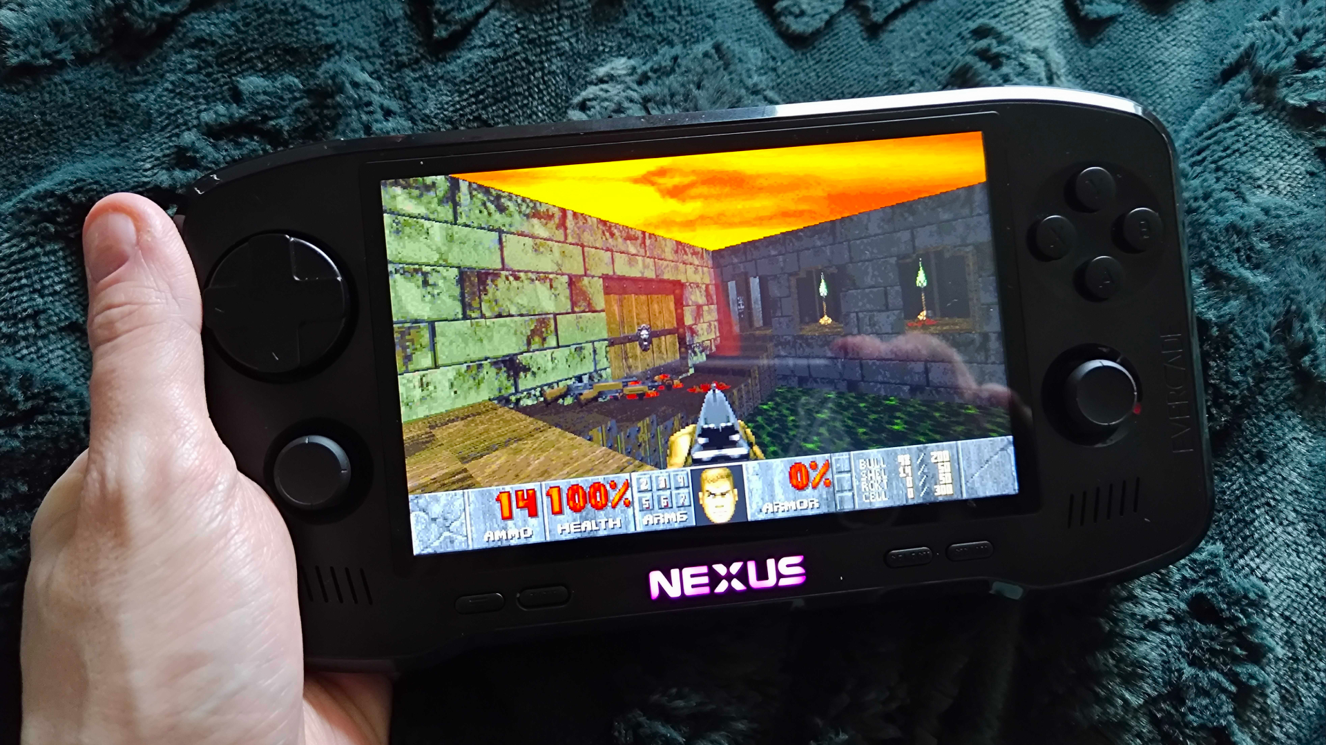 Hand holding Evercade Nexus with DOOM gameplay on screen.