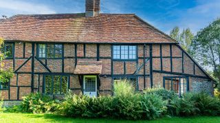 traditional brick cottage with a tiled roof, dark frame windows and a white door