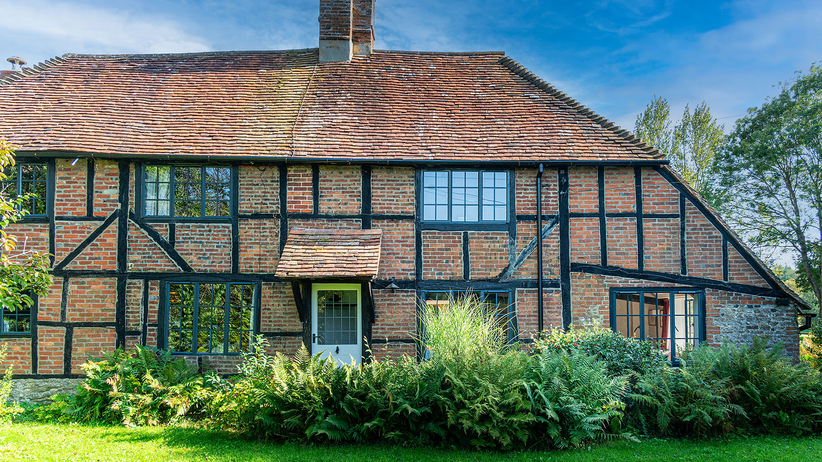 traditional brick cottage with a tiled roof, dark frame windows and a white door