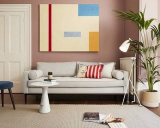 An off-white sofa in a living room with plaster pink walls
