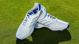 The stunning white and icy blue Adidas ZG23 Golf Shoe resting on the green
