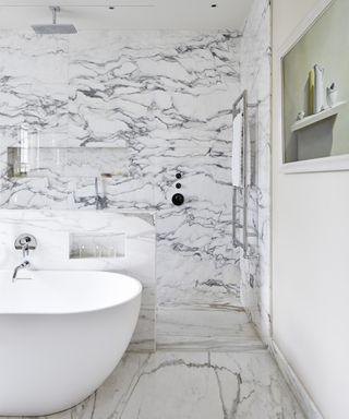 An example of shower tile ideas showing a bathroom with a marble-clad walk-in shower and a white standalone tub