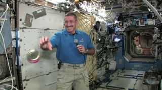 NASA astronaut Dan Burbank catches a floating can of cranberries on the International Space Station just before Thanksgiving.