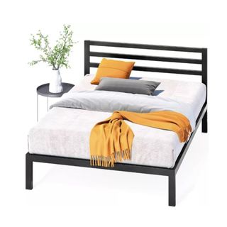 A black bed frame with white bedding and a yellow throw