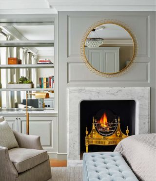 How to make a small bedroom look bigger in a cream bedroom with built in alcove storage over mirrors, and fire lit between