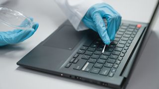 Scientists swabbing a laptop to see what bacteria it harbors.