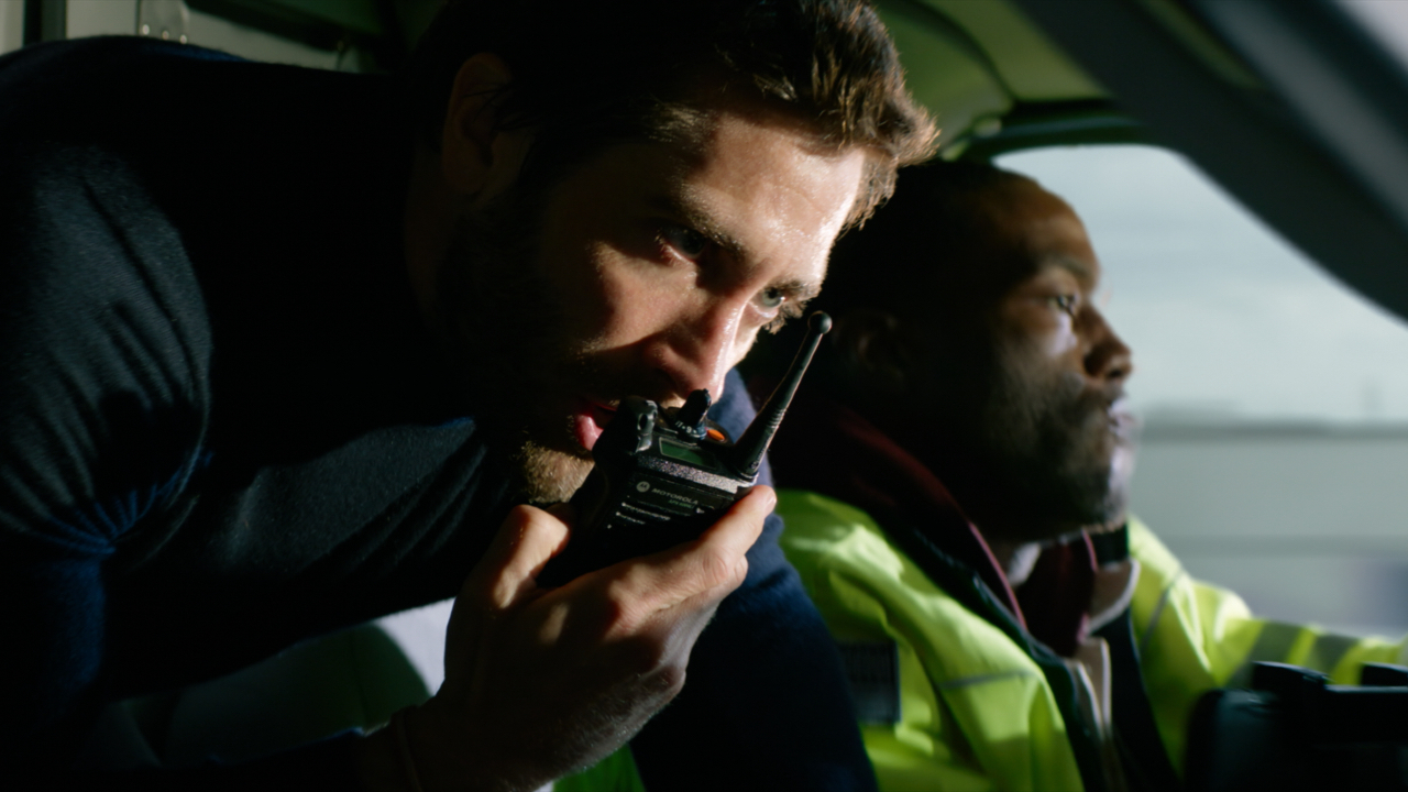 Jake Gyllenhaal talks on the radio as Yahya Abdul-Mateen II drives into Ambulance.