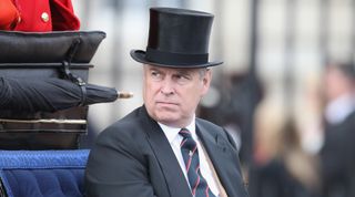 Prince Andrew rides in a carriage while wearing a top hat and a suit