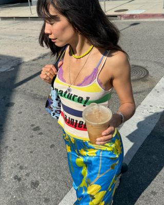 @nicole_huisman wears a printed skirt, a graphic tank top, a purple bralette, and a yellow necklace.