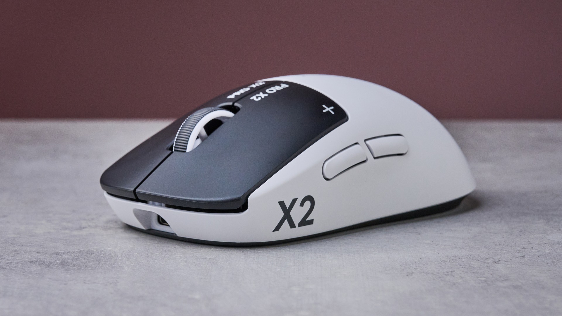 Three-quarter view of Logitech G Pro X2 Superstrike on white desk with pink wall in background