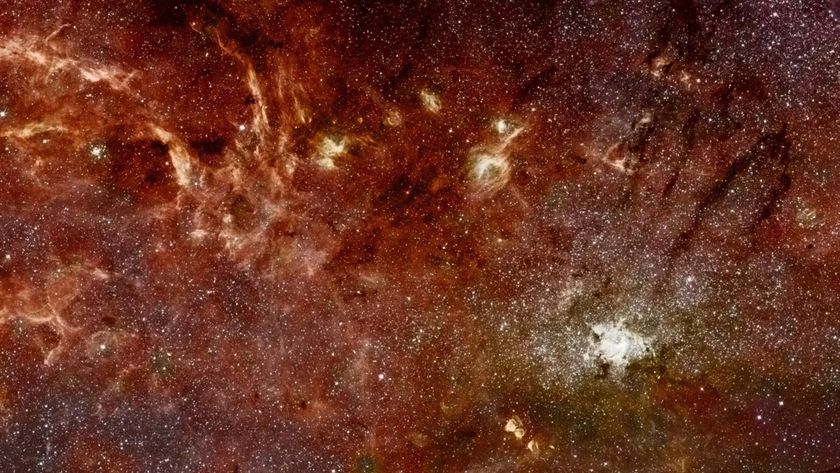A panorama shows glowing reddish gas mixed with stars in deep space