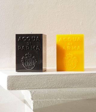 one square black candle and one square yellow candle on a white background