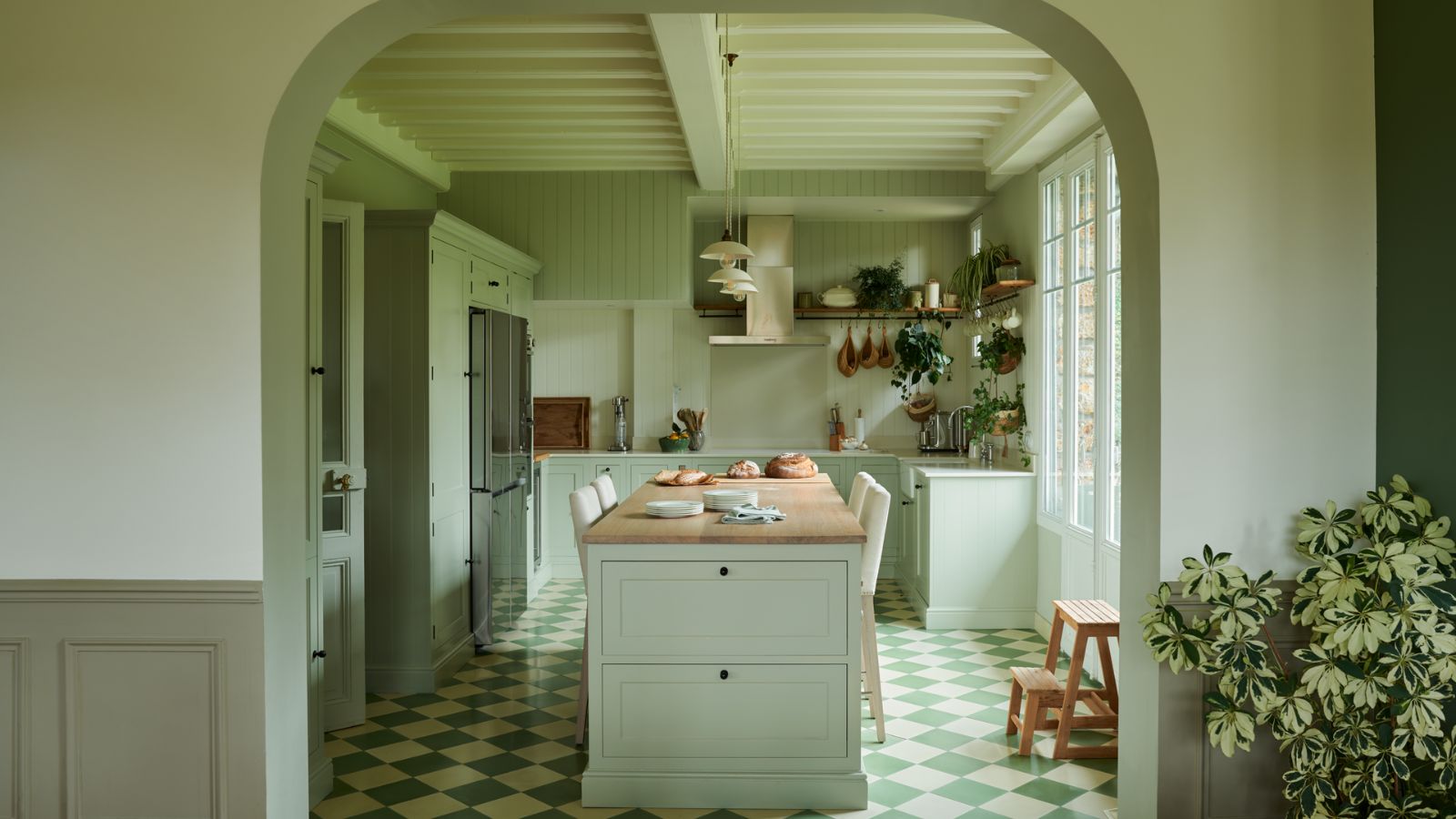 light green color-drenched kitchen with tiled floor, kitchen island and arched doorway