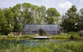 Green house in front of a pond