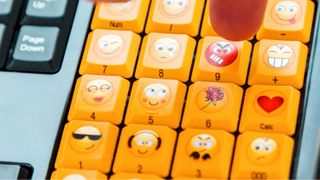 A finger presses a button on the keyboard with an angry emoji.