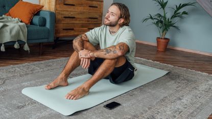 A man sitting on a yoga mat