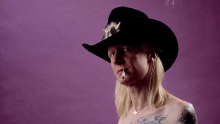 Johnny Winter studio headshot, wearing a cowboy hat and smoking a cigarette