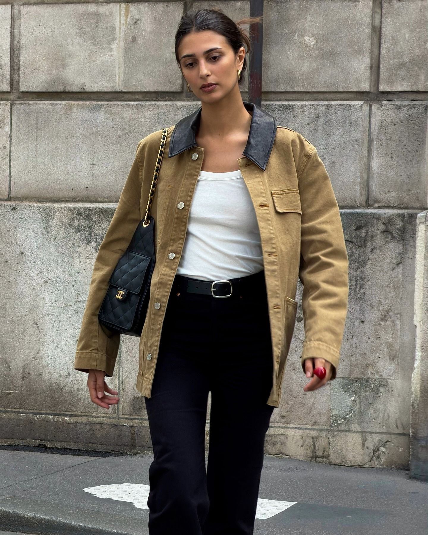 Salome wears a barn jacket, white tank, and black jeans.