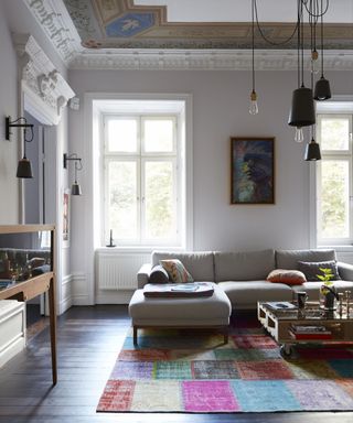 A white living room, multicolored rug and beige sofa with a variety of living room lighting.