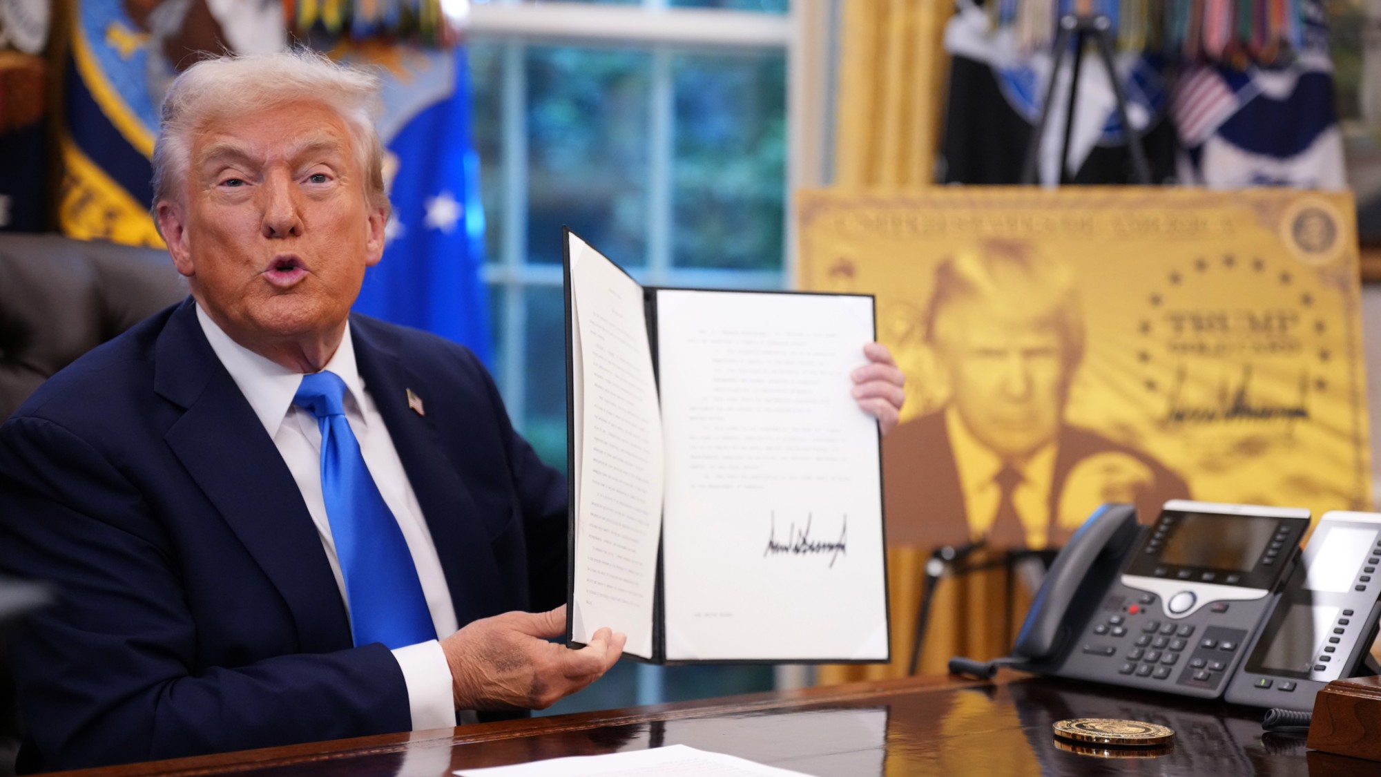 President Donald Trump holds up an executive order establishing the "Trump Gold Card" in the Oval Office at the White House on September 19, 2025 in Washington, DC. Trump signed a series of executive orders establishing the &ldquo;Trump Gold Card&rdquo; and introducing a $100,000 fee for H-1B visas. The "Trump Gold Card" is a visa program that allows foreign nationals permanent residency and a pathway to U.S. citizenship for a $1 million investment.