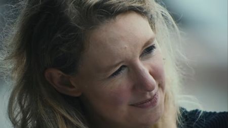 An extreme close up of Elizabeth Holmes looking to her left with messy hair in You Can See Everything