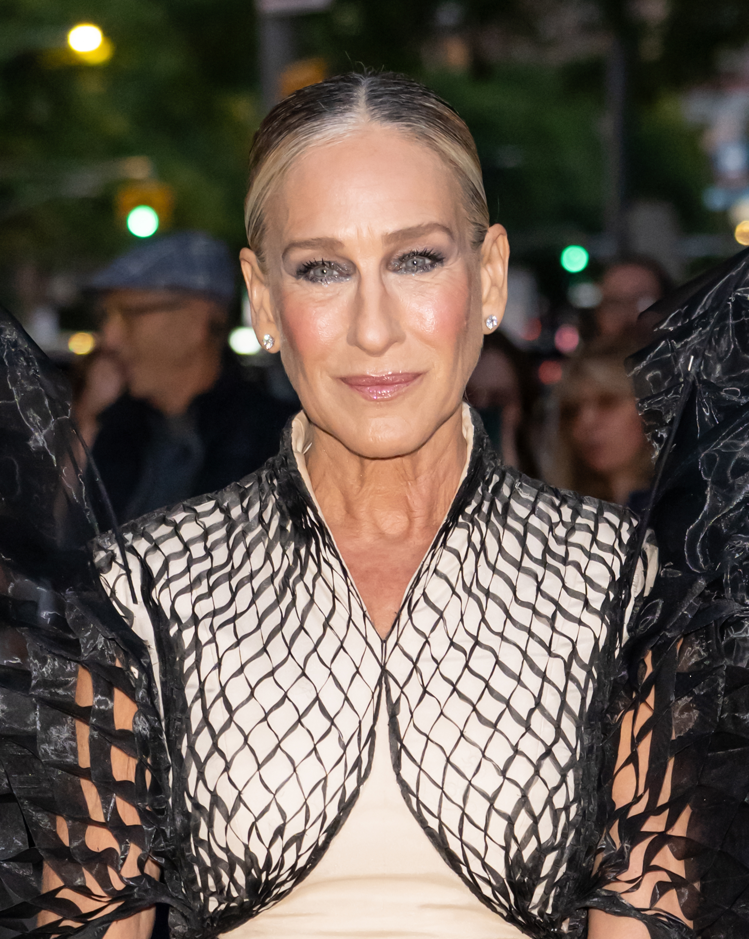 a paparazzi photo of a white woman with her hair pulled back and wearing dark eye makeup