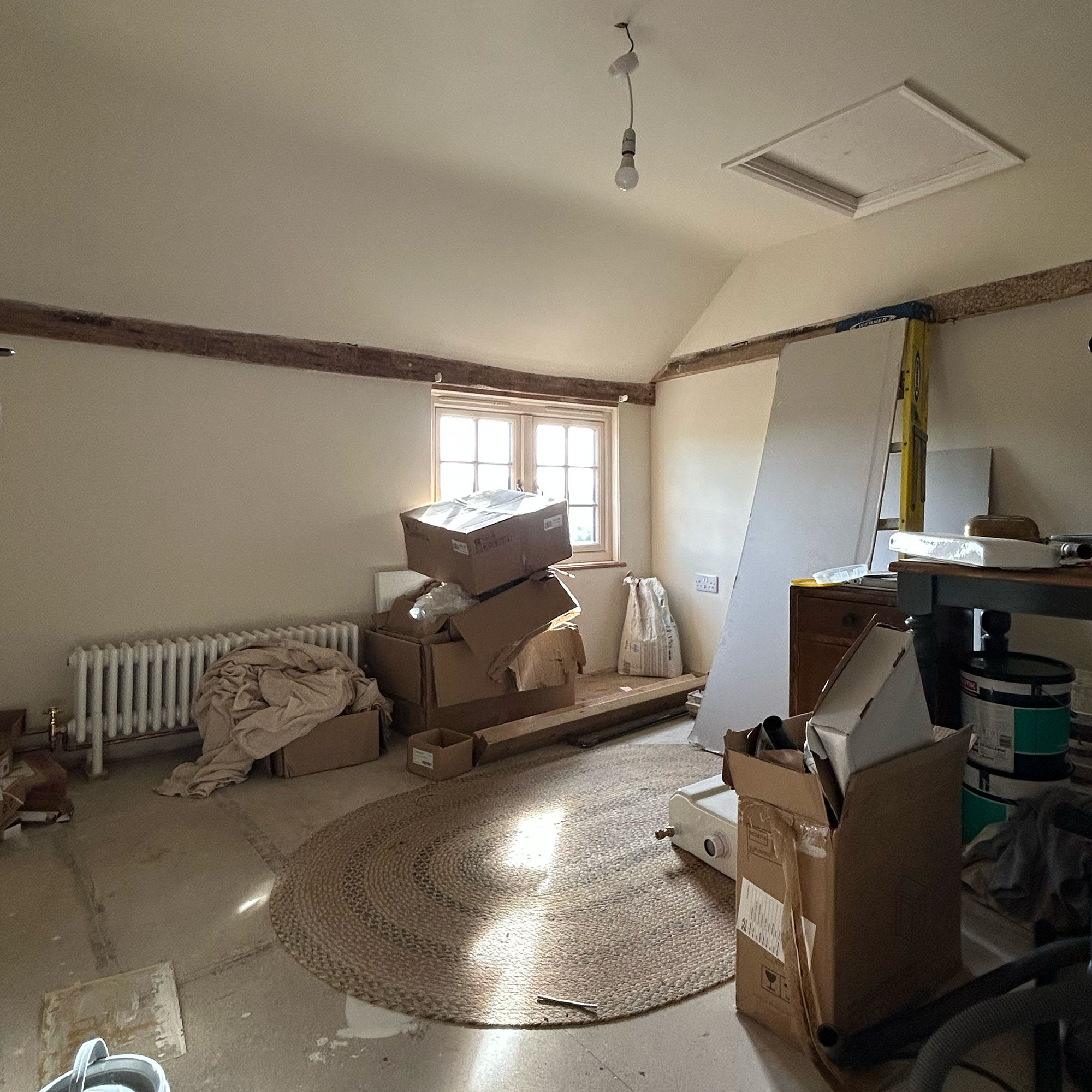 Room mid-renovation with unfinished flooring and cardboard boxes