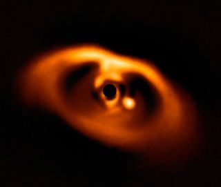 A molten orange oval ring around a similarly colored blob with a solid black circle at its center