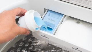 Fabric softener being added to a detergent drawer in a washing machine