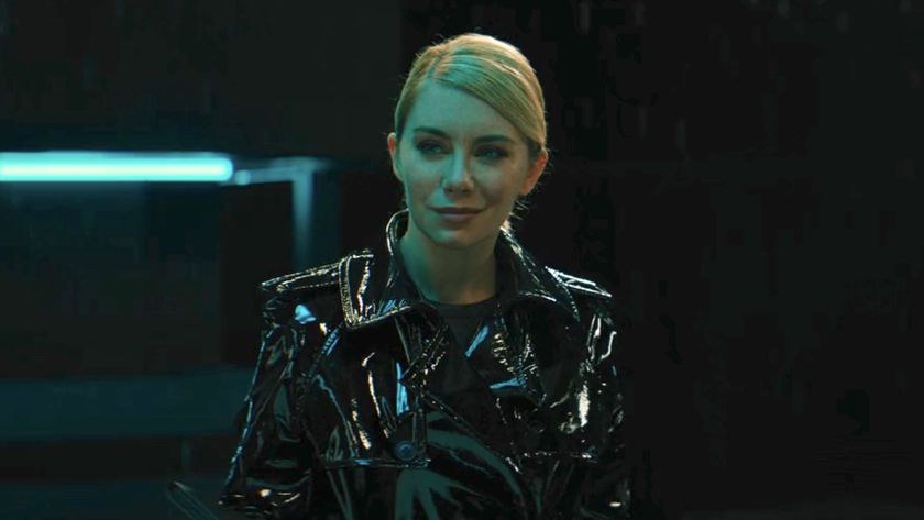 Jennifer Holland&#039;s Emilia Harcourt smirking and wearing reflective black jacket in Black Adam