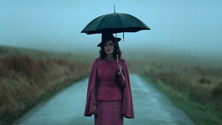 Sophie Rundle as Ada standing on the road and holding an umbrella in Peaky Blinders: The Immortal Man
