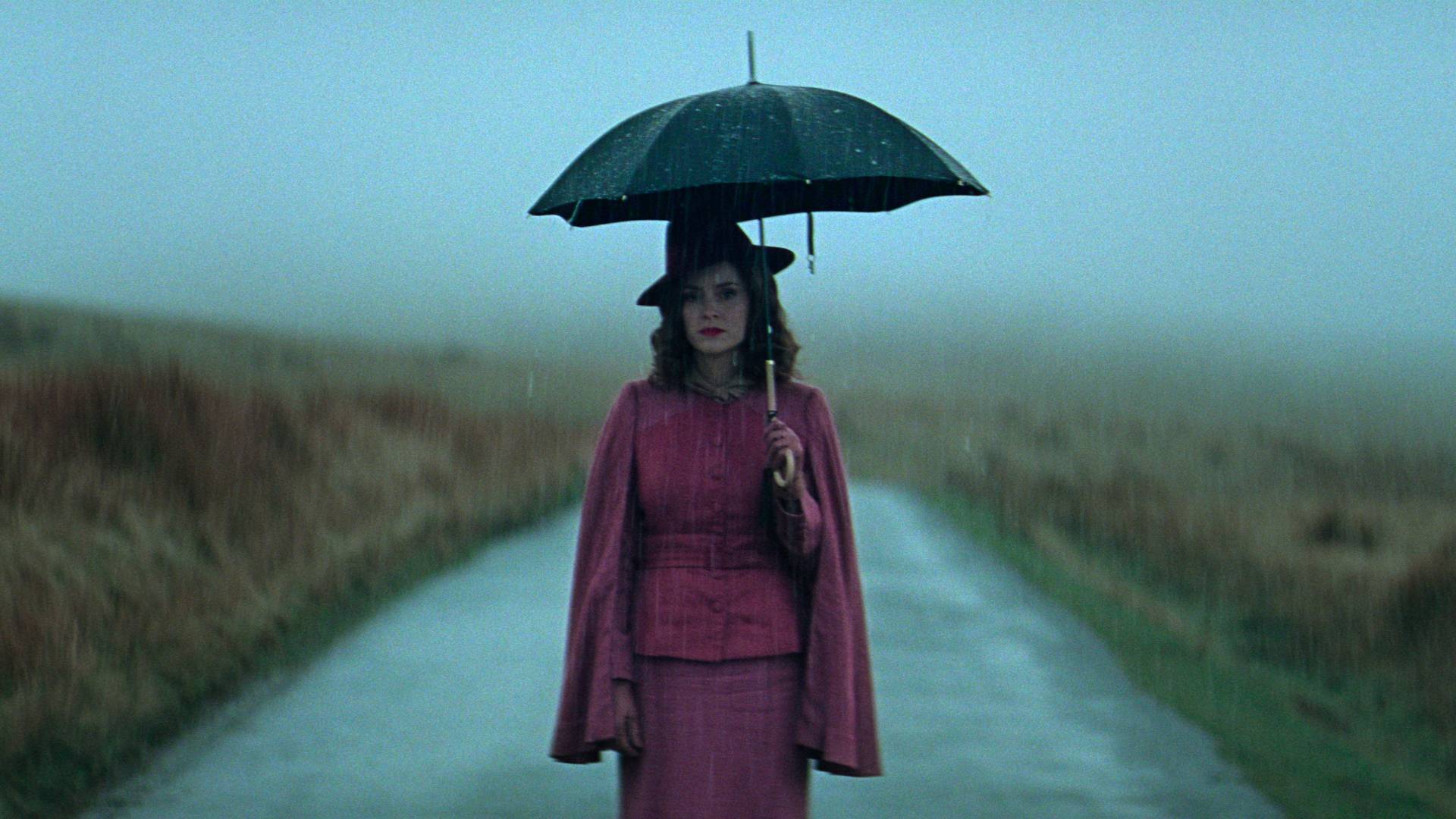 Sophie Rundle as Ada standing on the road and holding an umbrella in Peaky Blinders: The Immortal Man