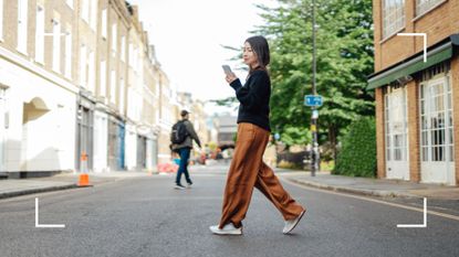 Woman walking after eating across the road, looking at mobile phone in hand