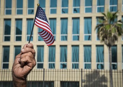 A U.S. flag is held up in front of the American embassy in Havana