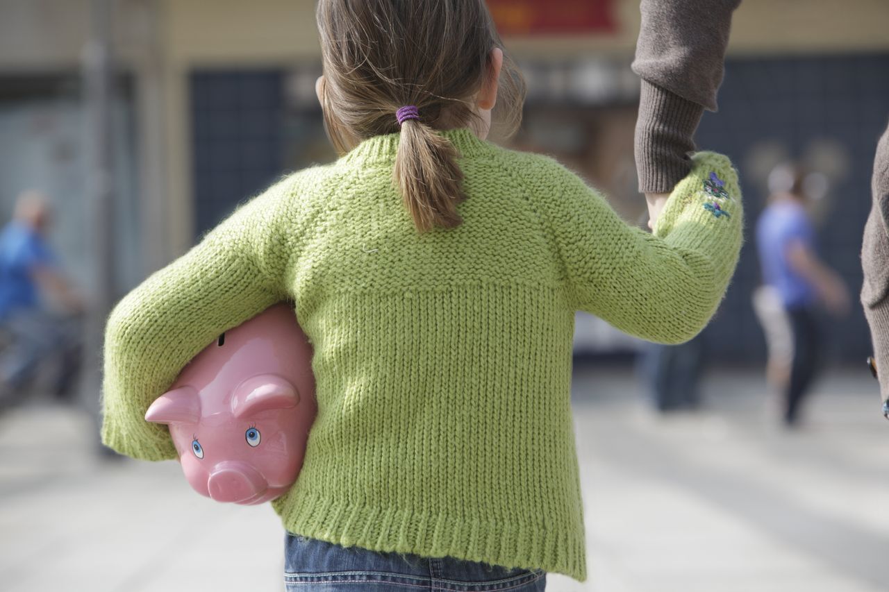 Young girl carrying piggy bank. 