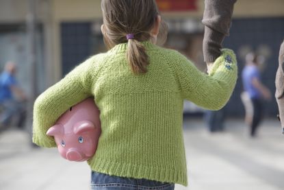 Young girl carrying piggy bank. 