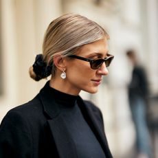 blonde woman wearing her hair in a low bun, wearing sunglasses and a black outfit