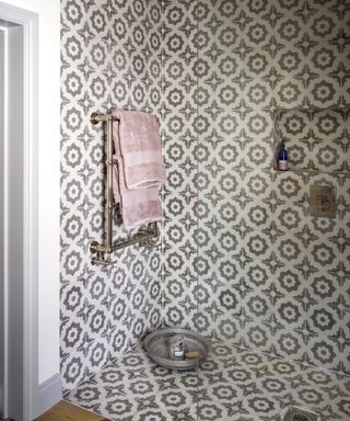 A walk-in shower with repeated patterned tiles on the walls and floor