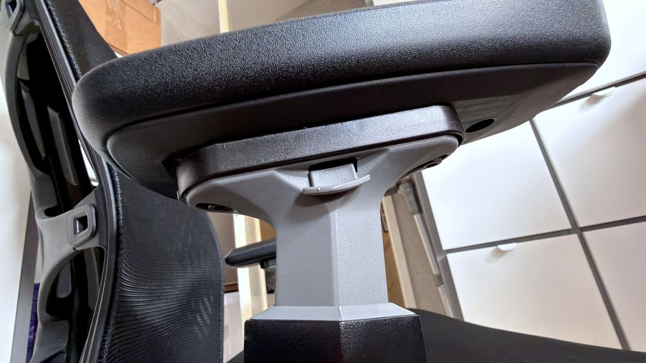 A photo of an Autonomous ErgoChair Ultra 2, showing a close-up view of an armrest and the latch used to adjust its height